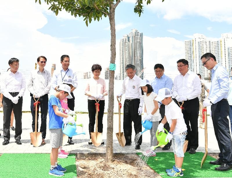 The Chief Executive and officiating guests plant a tree with a group of kids
